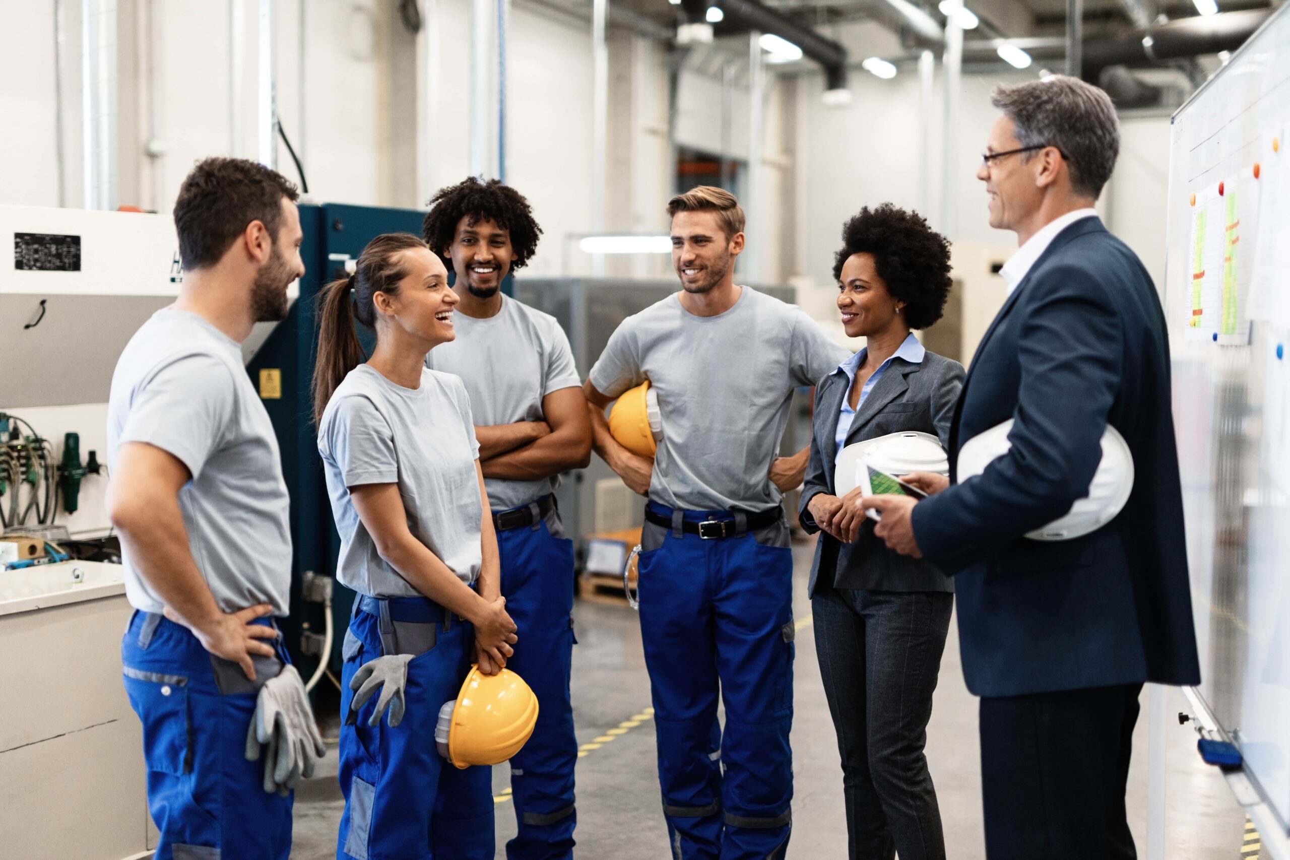 young-happy-female-worker-her-colleagues-communicating-with-company-managers-factory-min